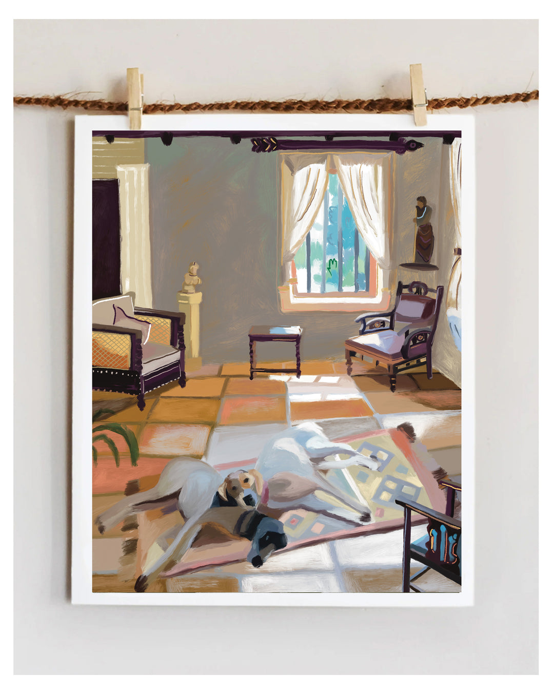 A framed art print depicting a cozy living room scene with two dogs lying on a patterned rug, hung on a rope with wooden clips against a white wall.