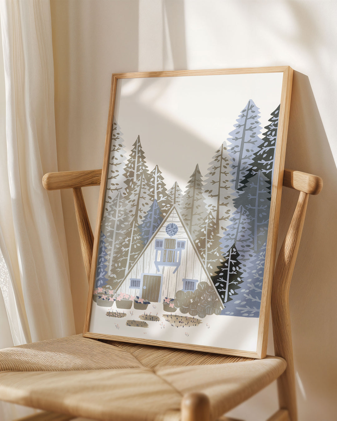 Framed Art Print titled 'Alpine Retreat' by Little Berries Studio, placed on a wooden chair in a softly lit room.