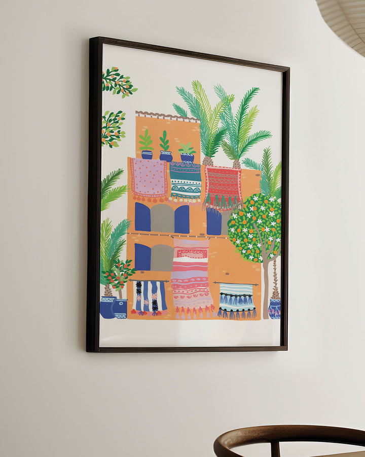 Ready-to-Hang Framed Wall Art of a Middle Eastern style abode with patterned rugs, potted plants, and palm trees by Little Berries Studio.