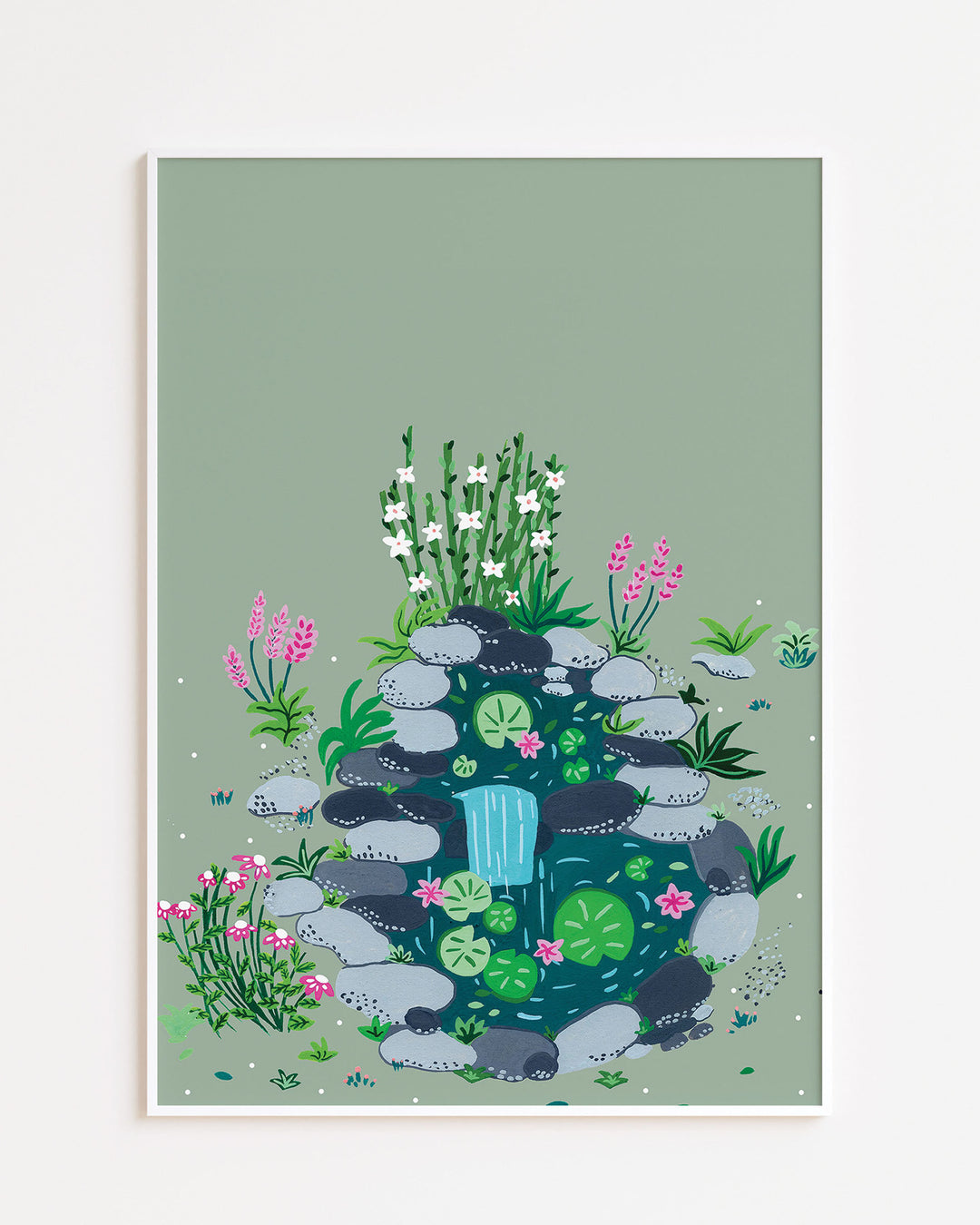 White Framed Art Print of a small, tranquil pond surrounded by smooth stones, blooming flowers, and lush greenery by Little Berries Studio.