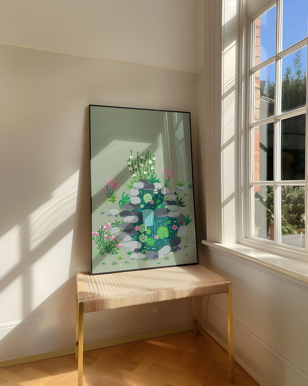 Framed Art Print titled 'Babbling Brook' by Little Berries Studio, resting on a woven bench near a sunlit window in a bright, airy room.