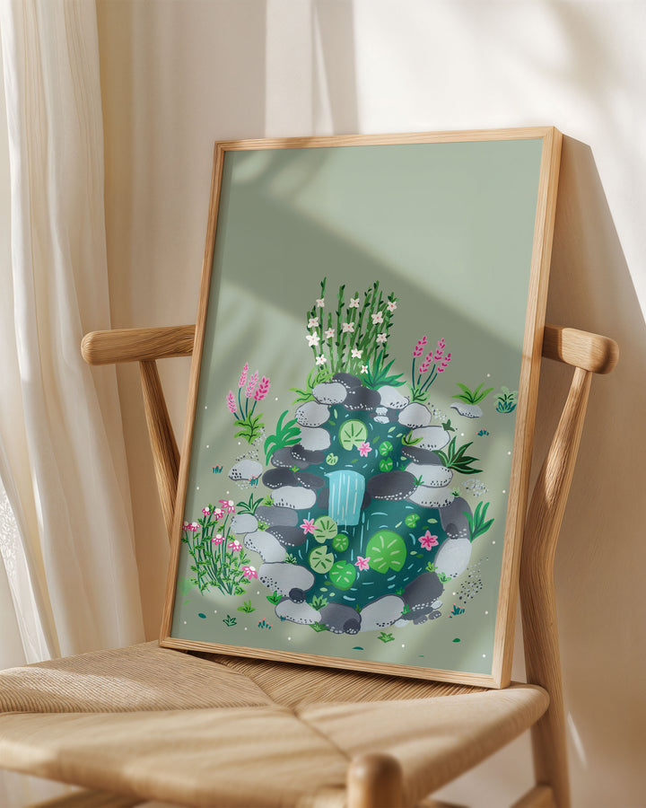 Framed Art Print titled 'Babbling Brook' by Little Berries Studio, placed on a wooden chair in a softly lit room.