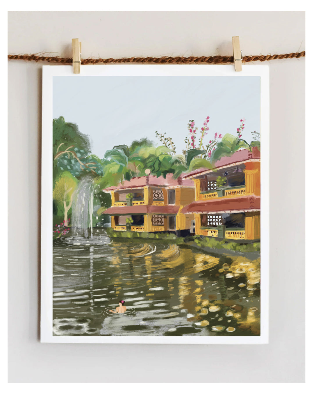 Artwork of a colorful house from Bhubaneswar by a pond with a fountain, hanging on a rope.