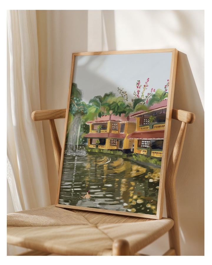 Framed painting of a scenic landscape with a house and garden from Bhubaneswar on a wooden chair.