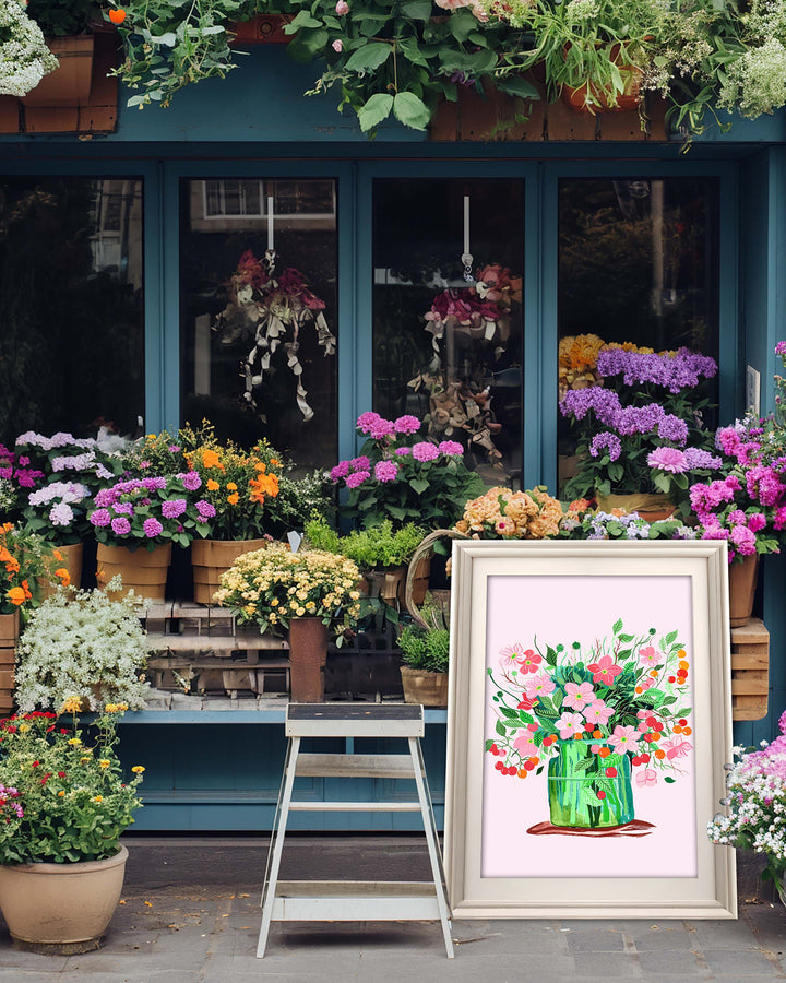A framed Art Print by Little Berries Studio featuring a vibrant arrangement of pink blossoms and green leaves in a colourful vase, displayed in front of a flower shop with various colourful plants and flowers.