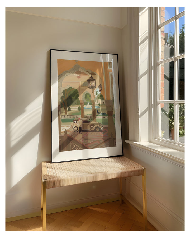 Framed artwork on a wall next to a window with sunlight streaming in showing courtyard of Jaipur.