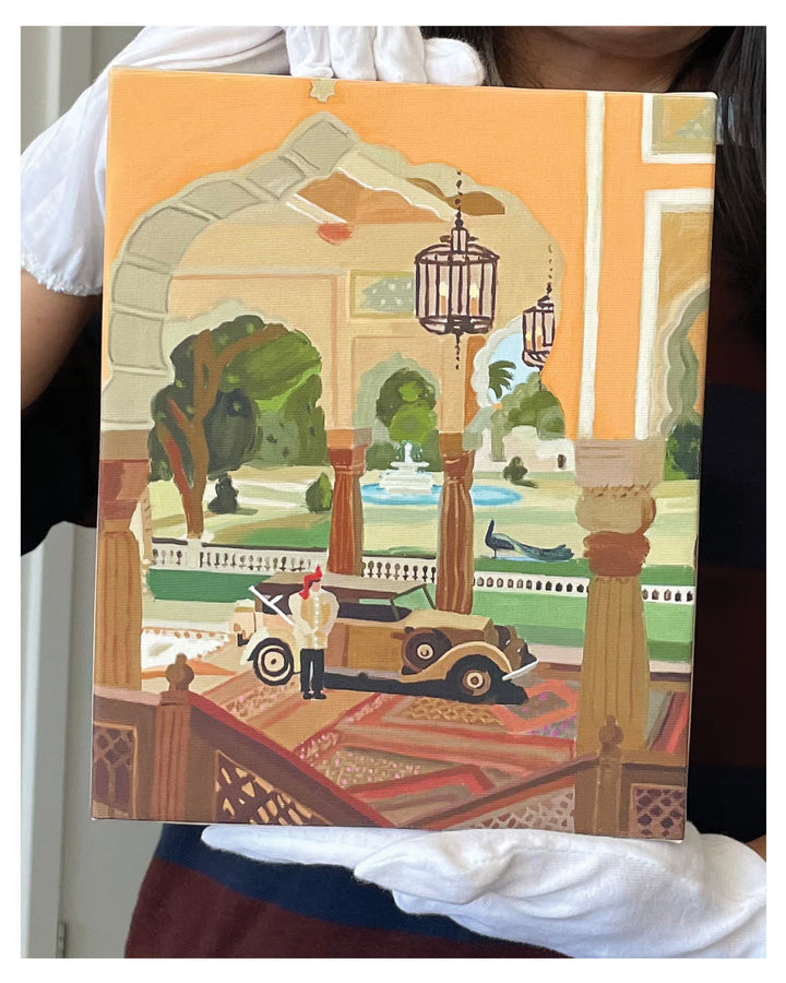 A person holds a square canvas painting depicting an elegant courtyard scene with a vintage car, arches, hanging lanterns, and a fountain in the background.