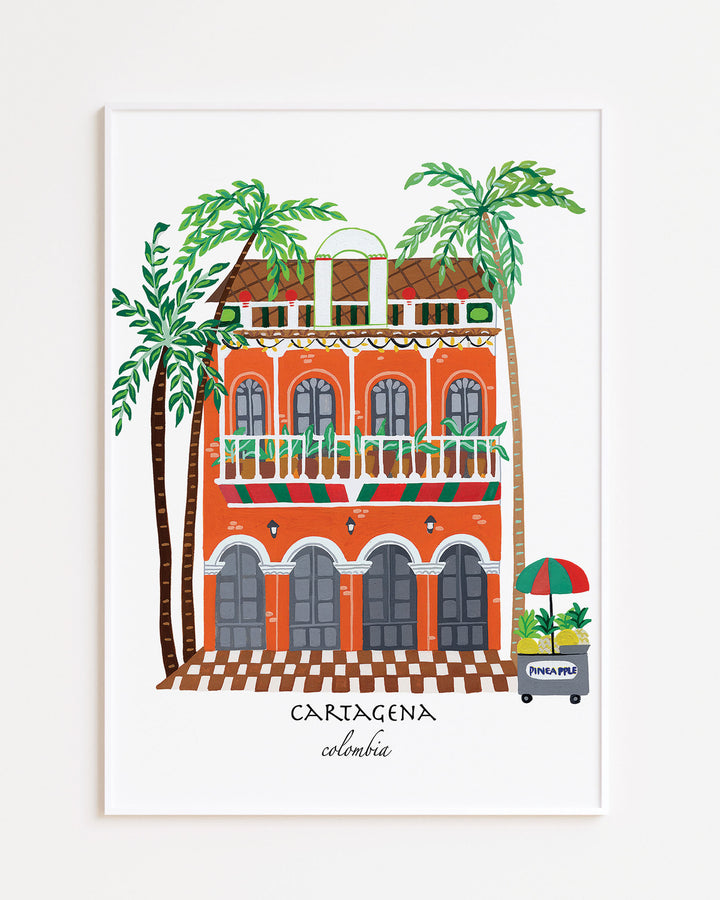 White Framed Artwork of a charming Cartagena building with vibrant orange facade, green balconies, and palm trees, capturing the lively spirit of Colombia.