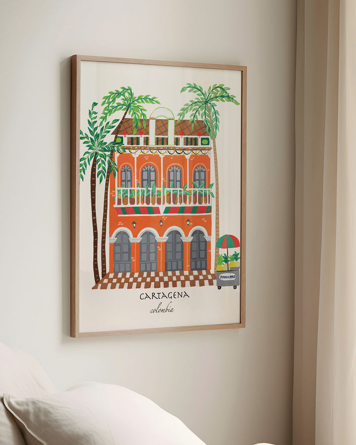 Framed Wall Art of a charming Cartagena building with vibrant orange facade, green balconies, and palm trees, capturing the lively spirit of Colombia.