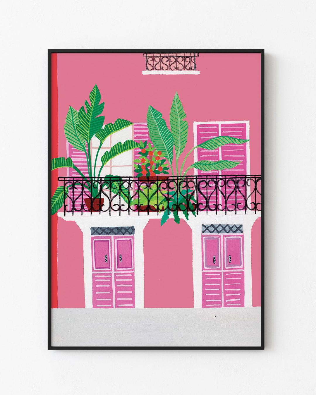 Black Framed Artwork of a vibrant pink building with a black wrought-iron balcony adorned with potted tropical plants and bold pink shutters.