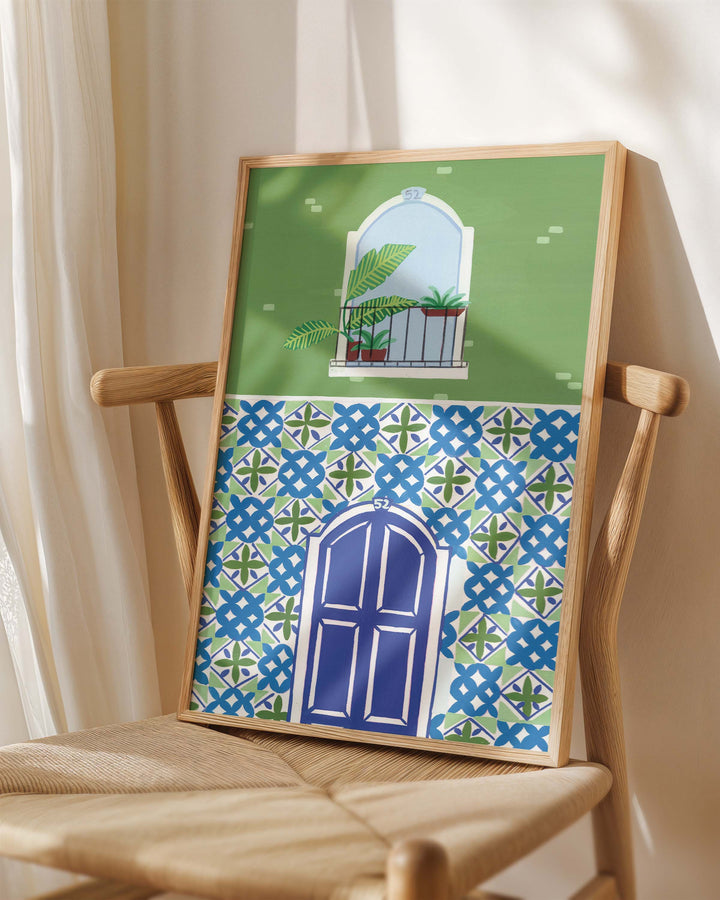 Framed Art Print titled 'Door Mediterranean Mosaic' by Little Berries Studio, placed on a wooden chair in a softly lit room.