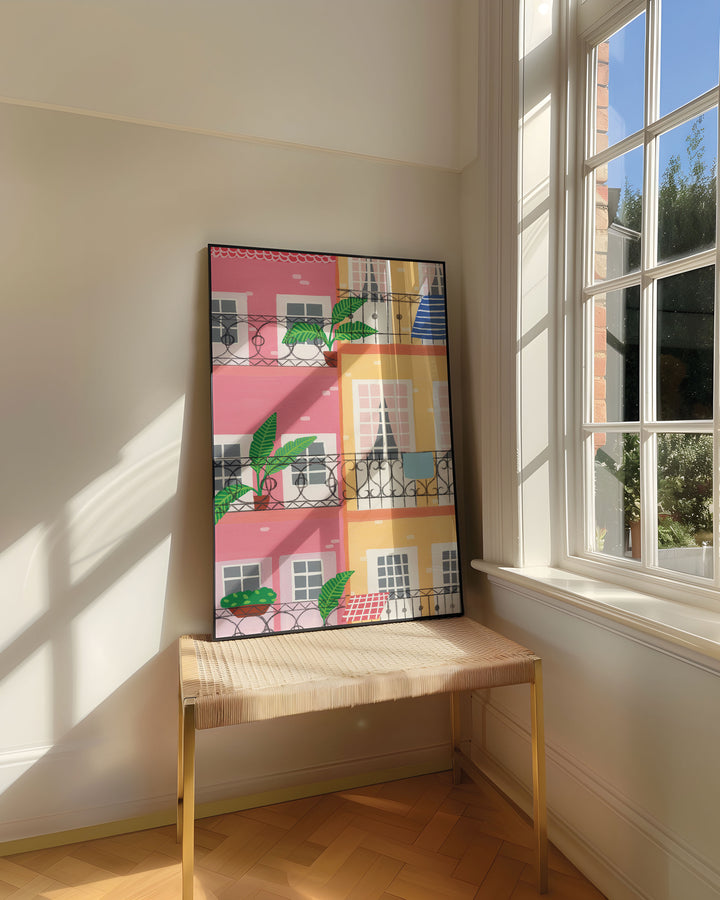 Framed Art Print titled "Door Urban Pastels" by Little Berries Studio, resting on a woven bench near a sunlit window in a bright, airy room.
