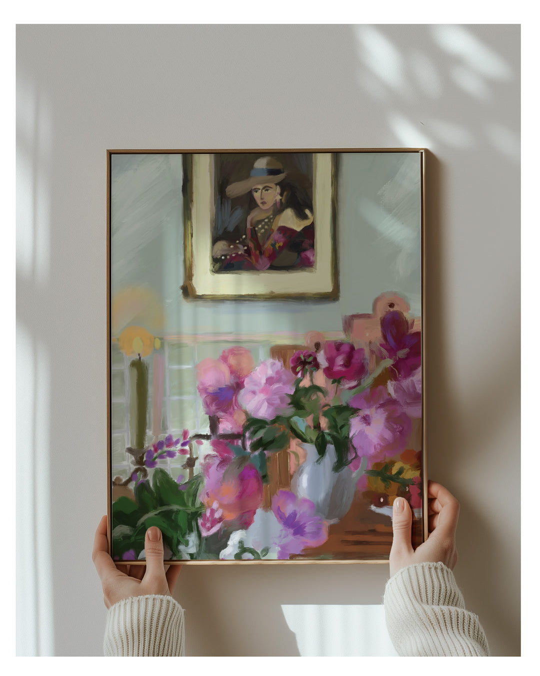 Person holding a framed painting of flowers against a wall with another painting.