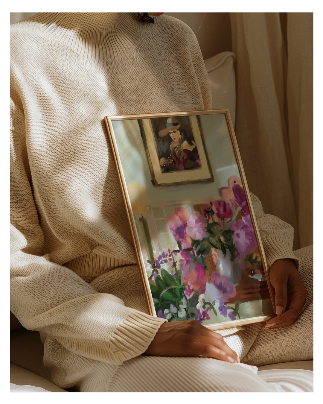 Person holding a framed painting of flowers in a warm, indoor setting