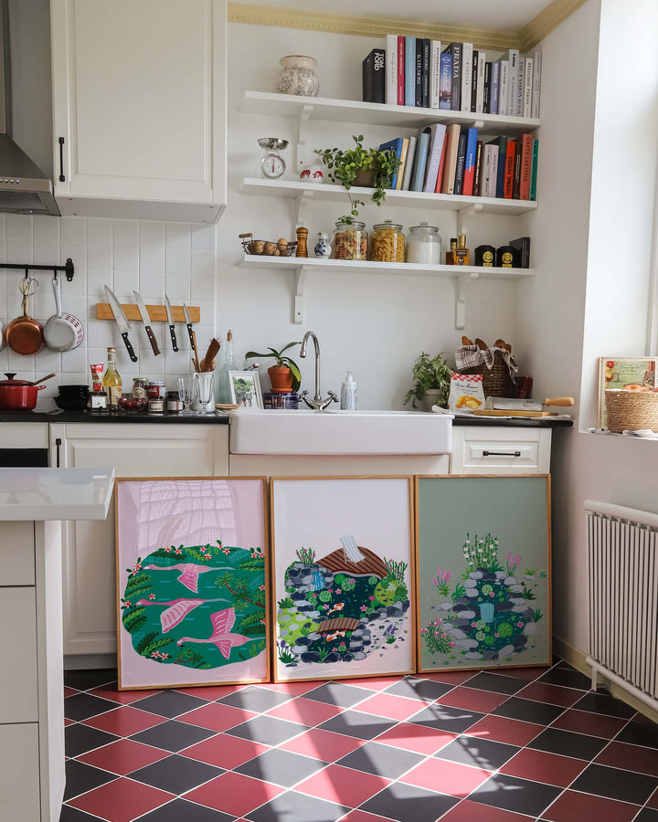 Three Framed Tropical Art Prints created by Little Berries Studio, leaning against a kitchen island with a cozy and rustic decor.