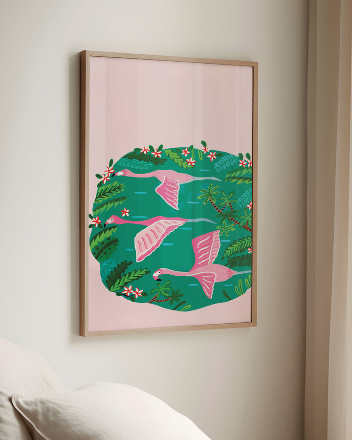 Framed Wall Art titled 'Flamingos Sanctuary' depicting pink flamingos flying over a green oasis filled with lush tropical plants and red and white flowers, created by Little Berries Studio.