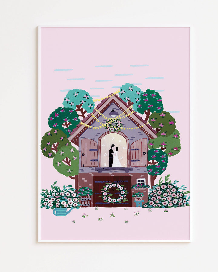 White Framed Art Print of a couple embracing inside a small cottage adorned with flowers and surrounded by colourful trees, with a pink sky in the background created by Little Berries Studio.
