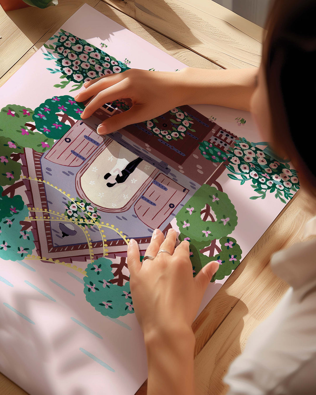 An Archival Art Print of a couple embracing inside a small cottage adorned with flowers and surrounded by colourful trees, with a pink sky in the background created by Little Berries Studio.