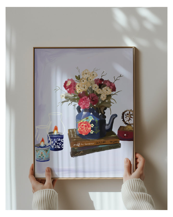 Framed artwork of a still life scene with flowers and books held by hands.