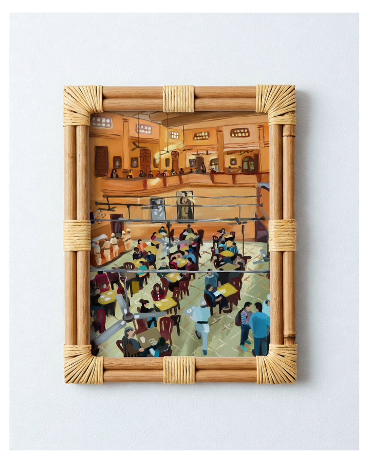 Framed artwork of a busy restaurant interior with a wicker frame.