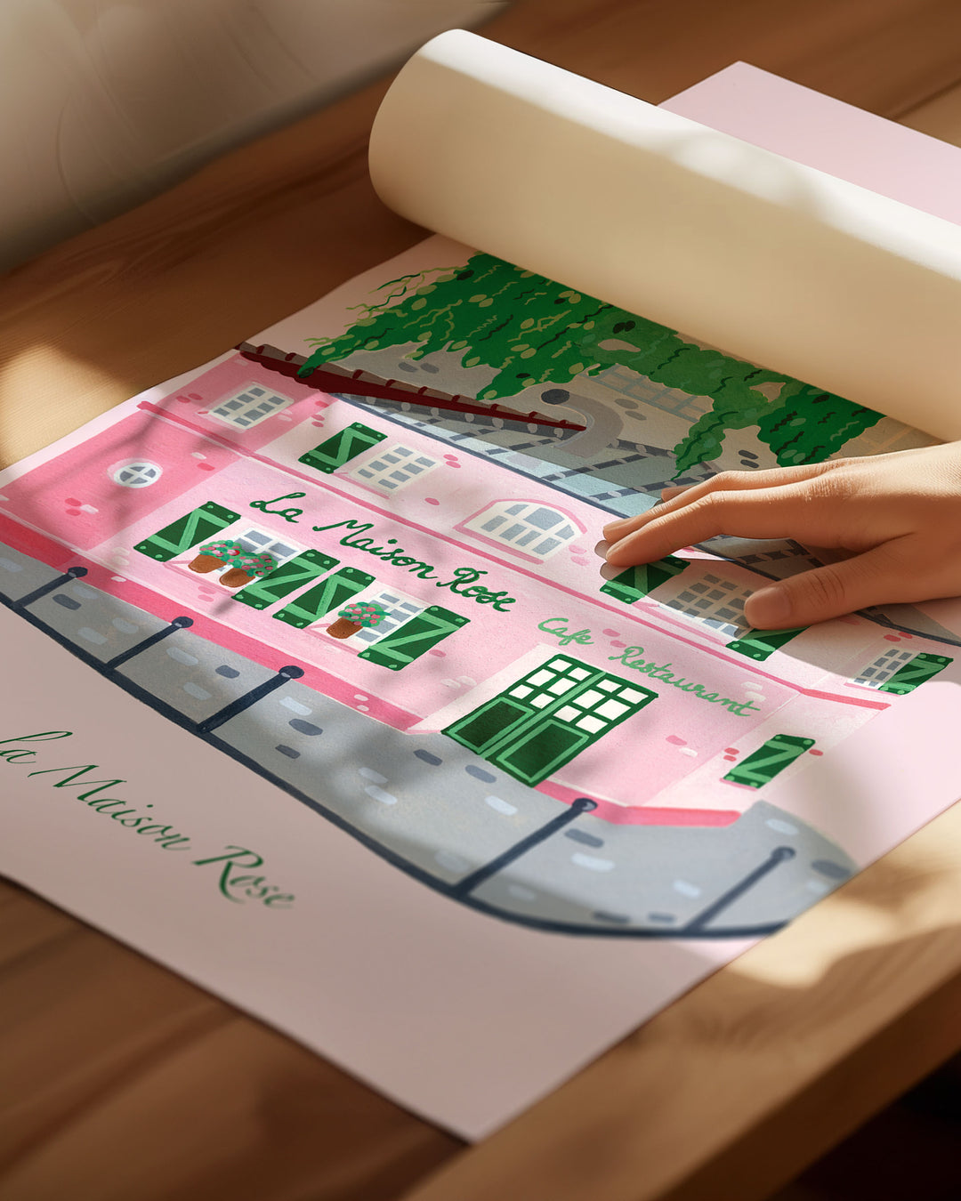 Archival Art Print of La’Maison Rose café in Montmartre, Paris, by Little Berries Studio, featuring a pink building with green shutters and lush green plants cascading from the roof.