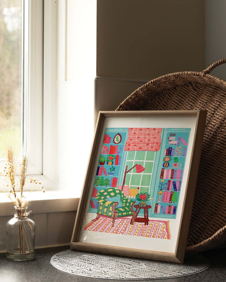 Framed Artwork depicting a colourful reading nook with a comfy chair, bookshelves, and charming decor, titled 'Literary Retreat' by Little Berries Studio.