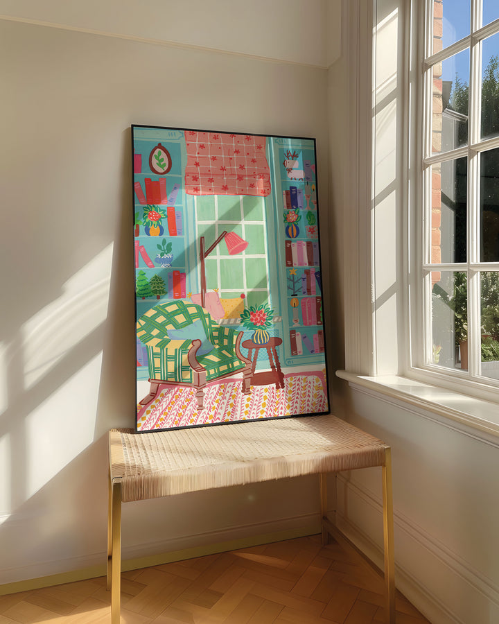 Framed Art Print titled 'Literary Retreat' by Little Berries Studio, resting on a woven bench near a sunlit window in a bright, airy room.