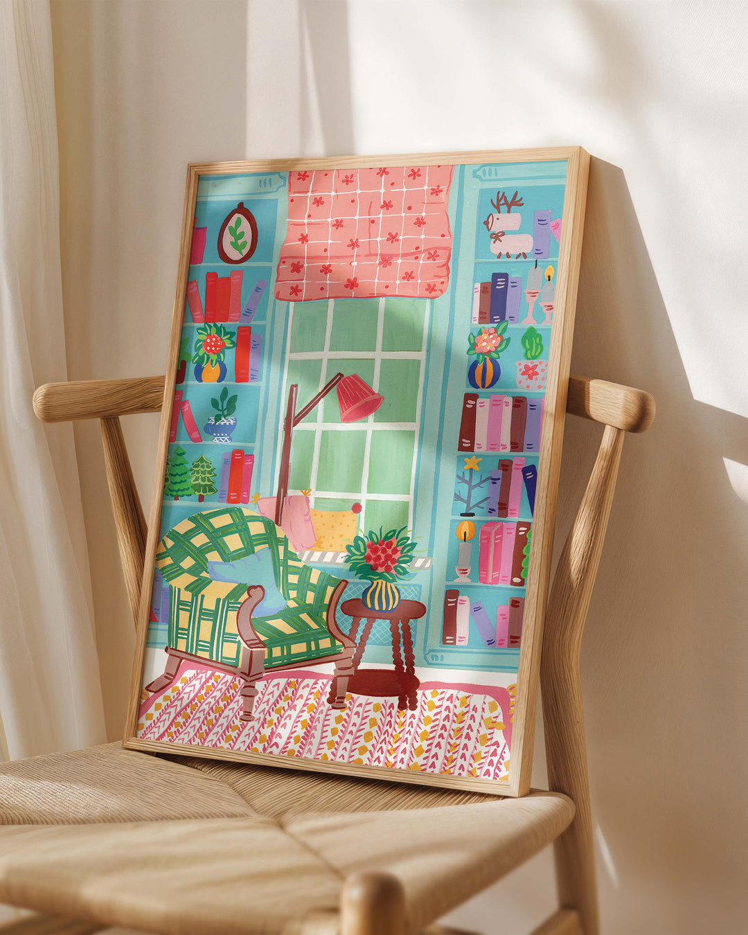 Framed Art Print titled 'Literary Retreat' by Little Berries Studio, placed on a wooden chair in a softly lit room.