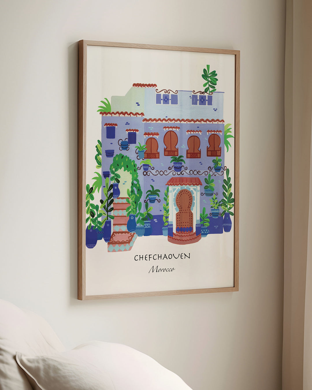 Framed Wall Art of a traditional Moroccan house in Chefchaouen by Little Berries Studio, featuring blue and white architecture, arched windows, and lush green plants.