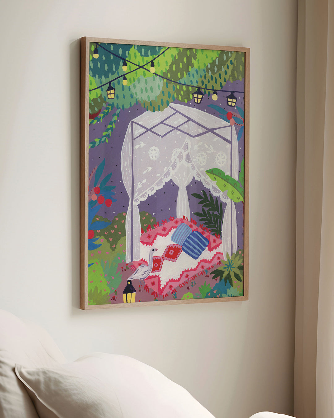 Framed Wall Art depicting a cozy outdoor scene under a canopy of trees. The centre features a draped canopy bed adorned with lace curtains, resting on a patterned red and white blanket with colourful cushions.