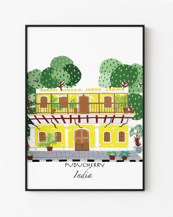 Black Framed Artwork of a traditional yellow building in Puducherry, India, surrounded by lush greenery. Archival Print by Little Berries Studio.