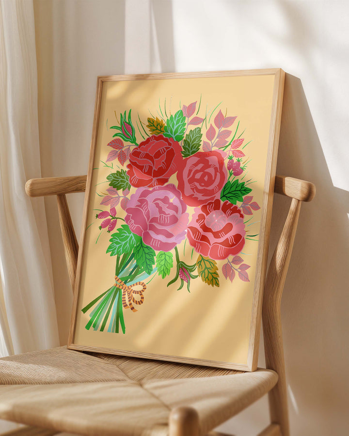 Framed Art Print titled 'Rose Reverie' by Little Berries Studio, placed on a wooden chair in a softly lit room.