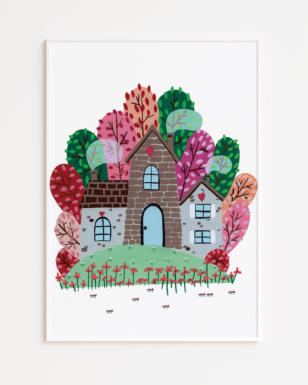White Framed Artwork of a cozy Smoke House with a blue door and heart details, surrounded by vibrant, colourful trees and blooming red flowers, ideal for decorating kids' rooms.