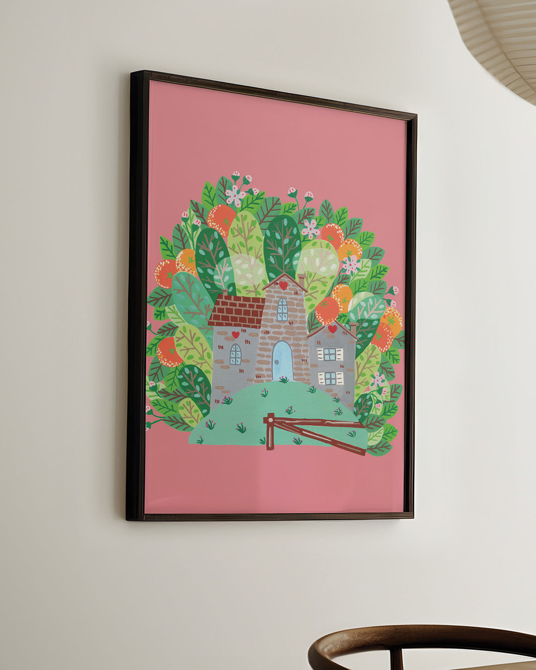 Ready-to-Hang Framed Wall Art of a cozy Smoke House with a blue door and heart details, surrounded by vibrant, blooming foliage on a pink background, ideal for decorating kids rooms.