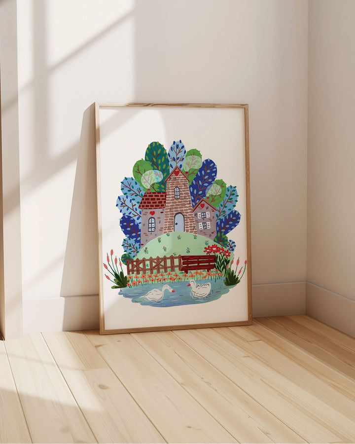 Framed Artwork of 'Smokehouse Lakeside Serenity' a cozy stone house by a serene lake with two swans, surrounded by colourful trees and flowers, placed in a sun-lit room.
