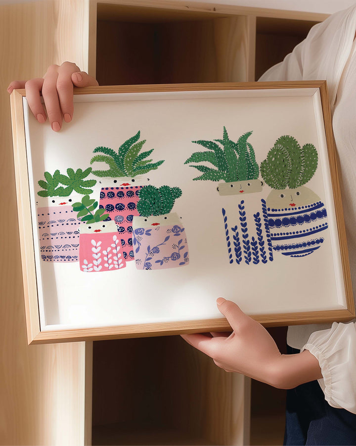 Person holding a Framed Archival Print showcases a collection of succulents in vibrantly patterned pots, created by Little Berries Studio.
