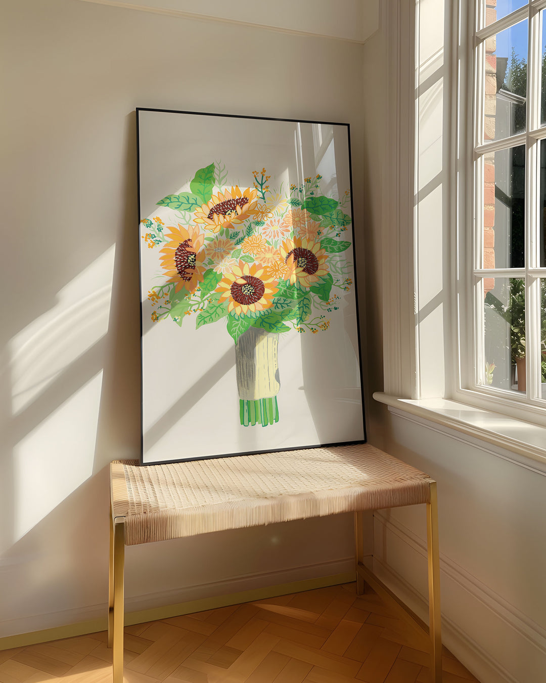 Framed Art Print titled 'Sunny Serenade' by Little Berries Studio, resting on a woven bench near a sunlit window in a bright, airy room.