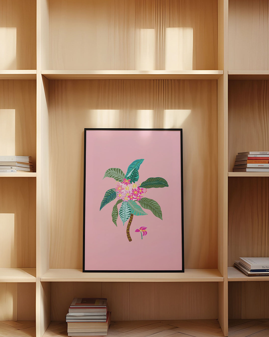 Framed Artwork titled 'Tropical Bloom', featuring vivid floral patterns set against a soft pink background placed in a library.