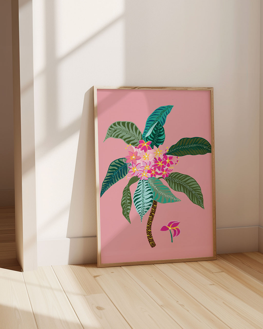 Framed Artwork titled 'Tropical Bloom', featuring vivid floral patterns set against a soft pink background in a sun-lit room.