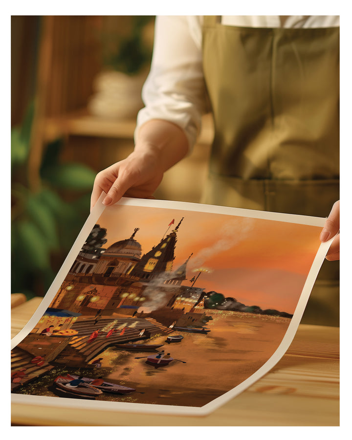Person holding a large print of a scenic artwork of Varanasi ghat on a wooden surface.