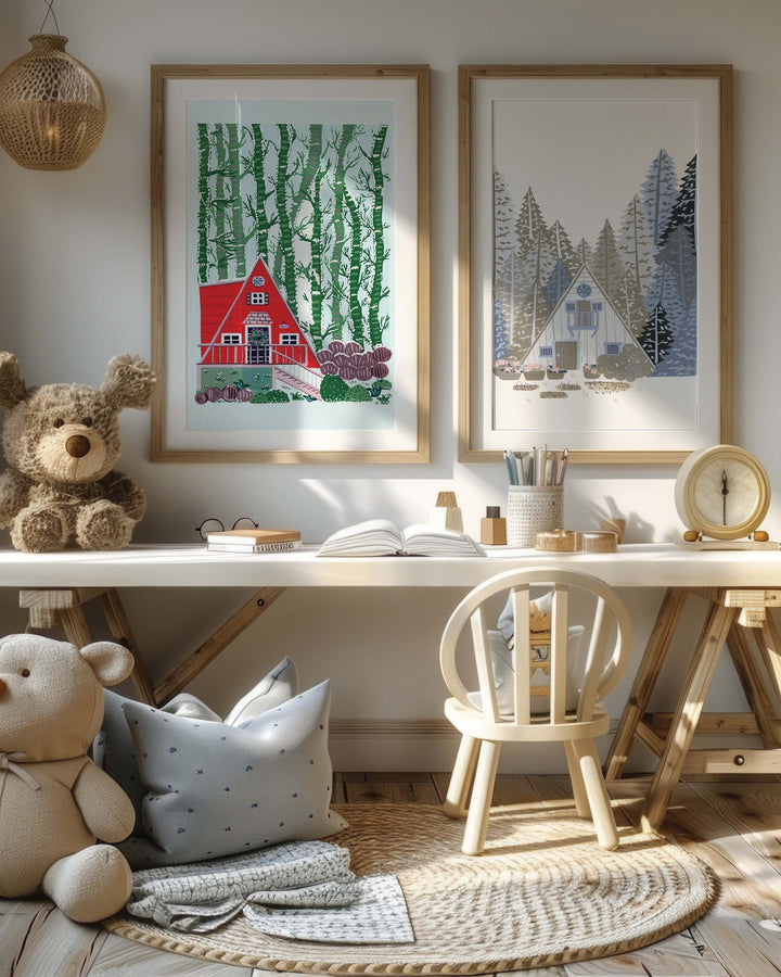 It features a cosy children's corner with warm, inviting decor. The focus is on two framed Art Prints. The Print on the left depicts a charming red A-frame cabin nestled amidst a dense stand of birch trees. The right Print shows a charming A-frame cabin nestled among towering pines.